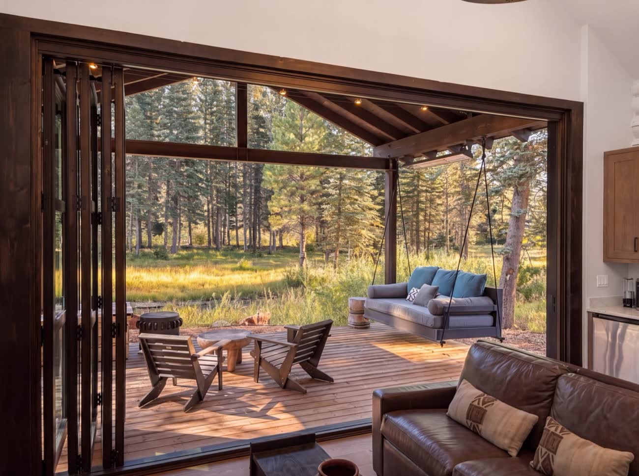 Lodge doors folded open to the porch and meadow